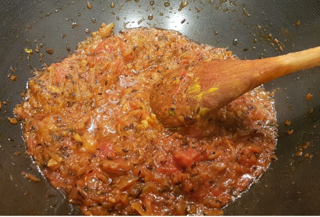 alu gobi mixing spices with onion tomato